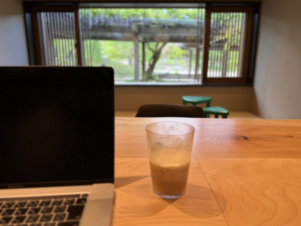 スタバ京都円山公園 菊の渓店　1階のコミュニティテーブルから見える額縁アートのような藤棚が見える窓