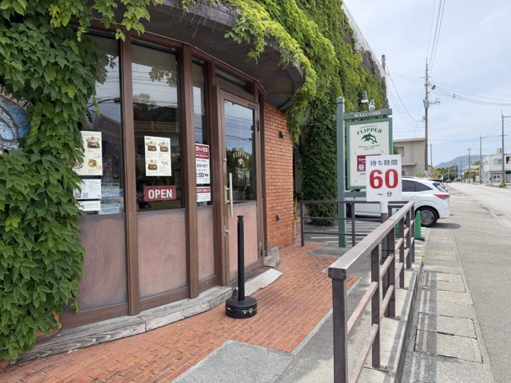 名護の人気ステーキ店ふりっぱーの外観　６０分待ちの表示。道路側からパイが買える